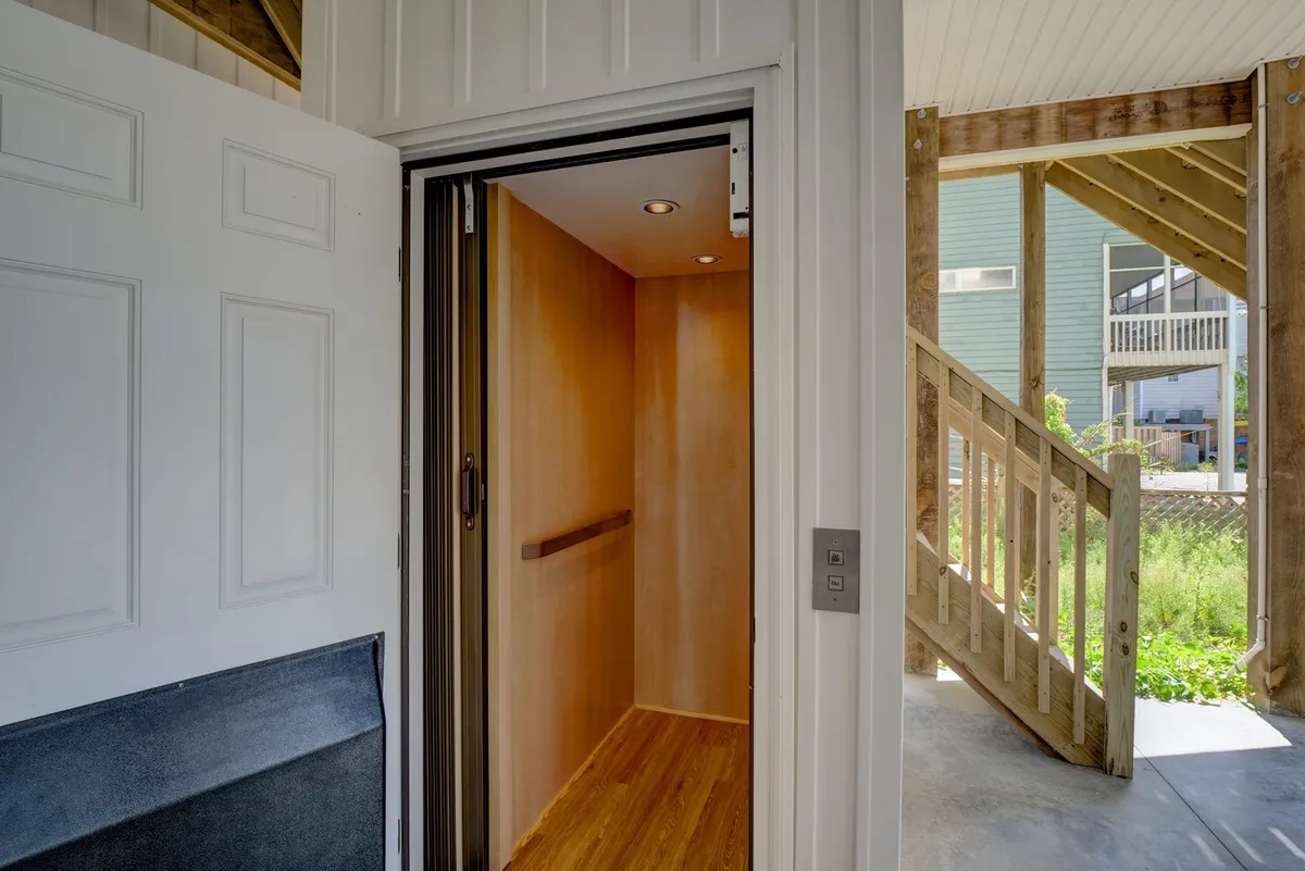 A view of the home’s residential elevator, adjacent to a doorway and staircase, offering a peek at the property’s accessibility feature within a clean, modern interior.