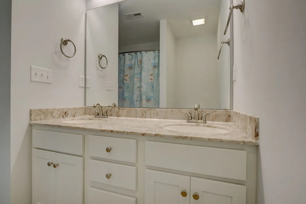A bright, functional bathroom with double sinks, mirrors, and modern fixtures. The space is designed for easy family use and morning routines, combining practicality with style.